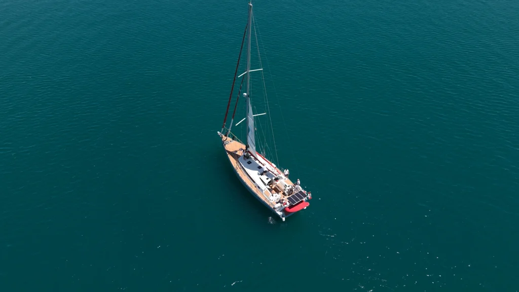 A sailboat drifts lonely on the calm, deep blue water and embodies the serene life at sea.