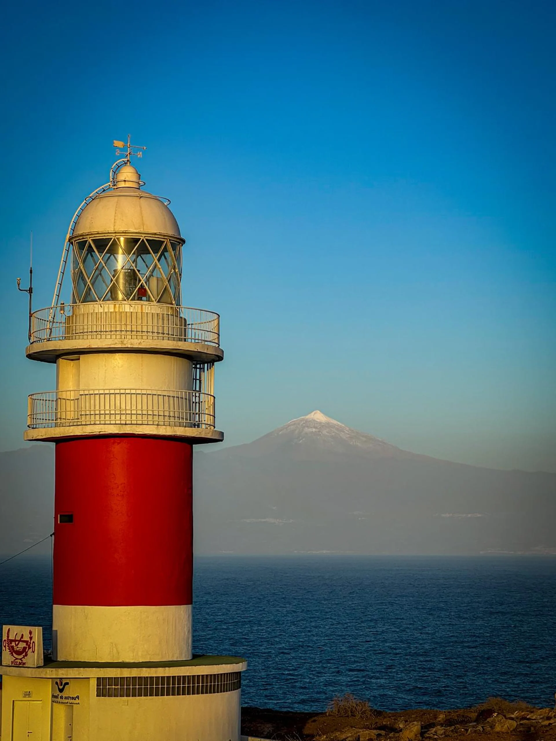 Rot-weißer Leuchtturm am Meer mit OceanLife-Kanaren Leg 1 - 261219 im Hintergrund.