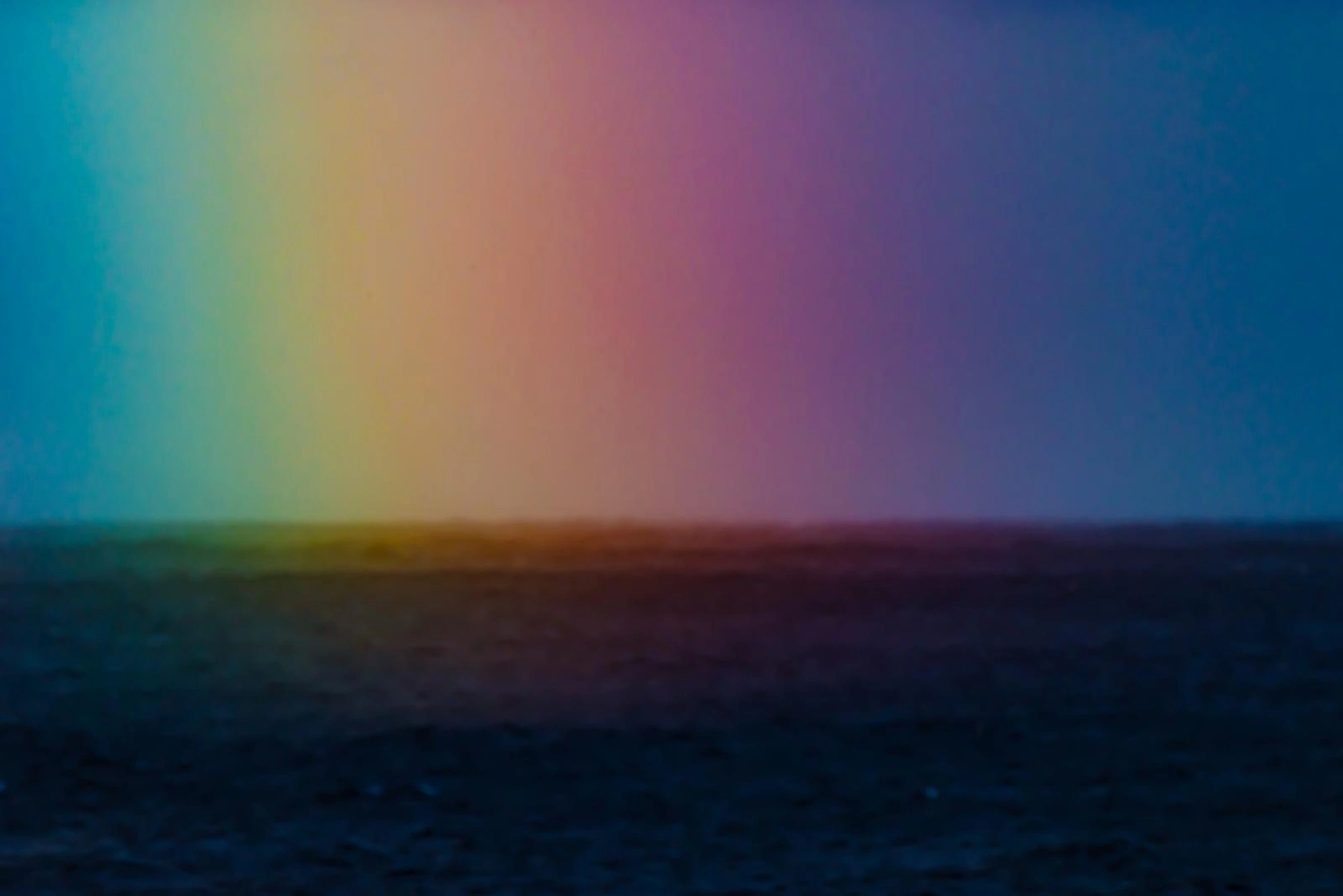 Ein leuchtender Regenbogen wölbt sich über einem ruhigen, dunklen Meer für OceanLife-Kanaren Leg 1 - 261219.