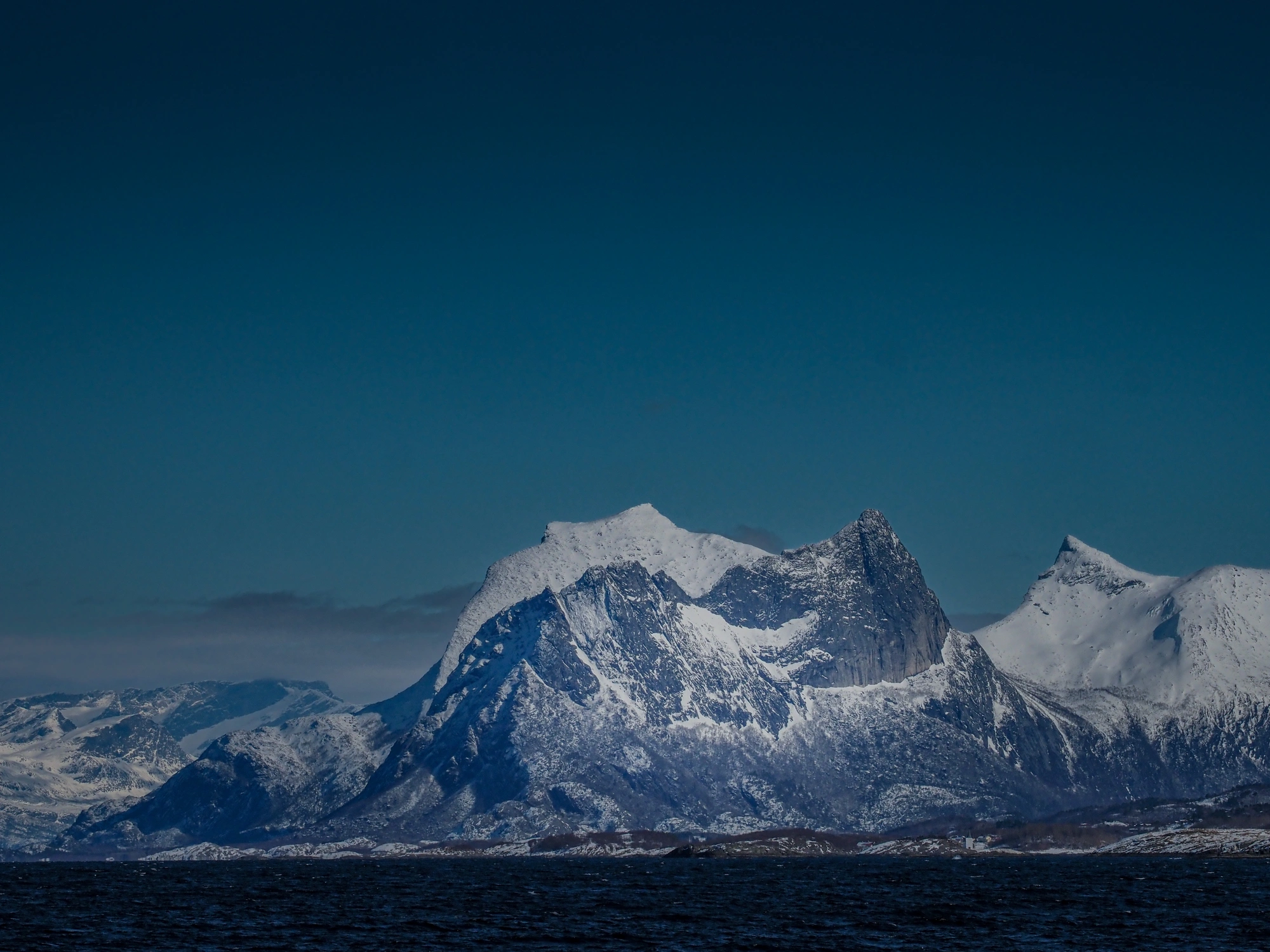 Schneebedeckte Berge unter blauem Himmel, mit Sail & Ski Lofoten 1 - 270320 im Vordergrund.
